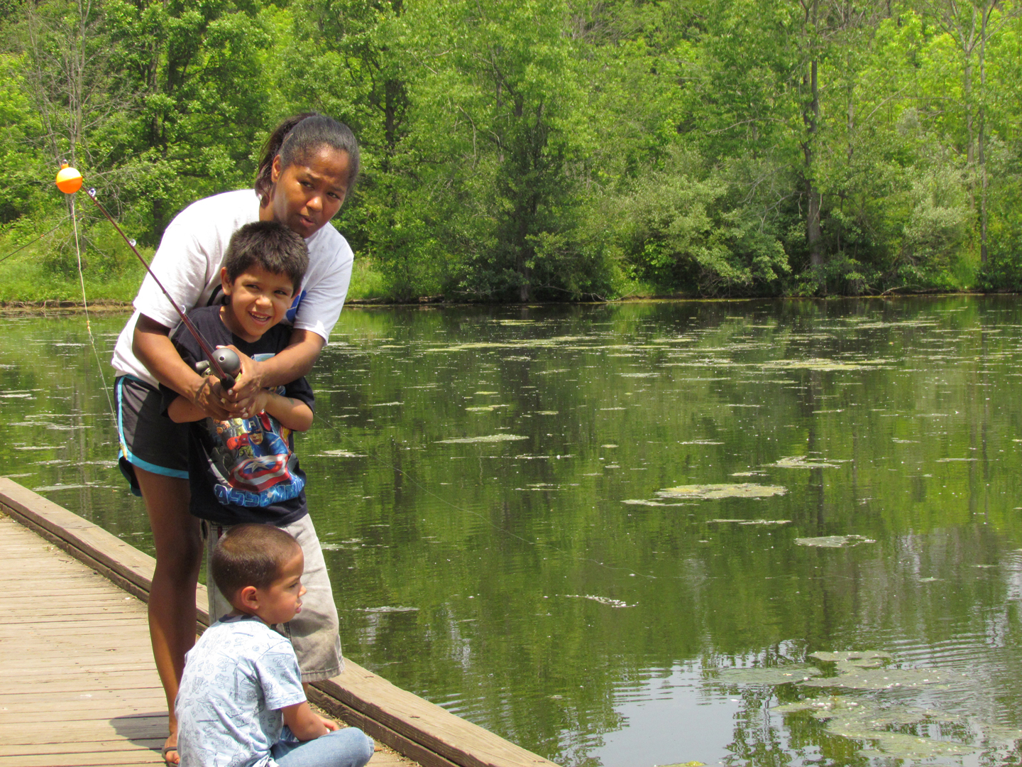 Adult helps young boy cast a fishing line into Schrock Lake at Sharon Woods Metro Park