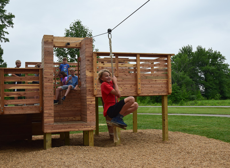 A kid takes off on the zipline on a play structure at Glacier Ridge.
